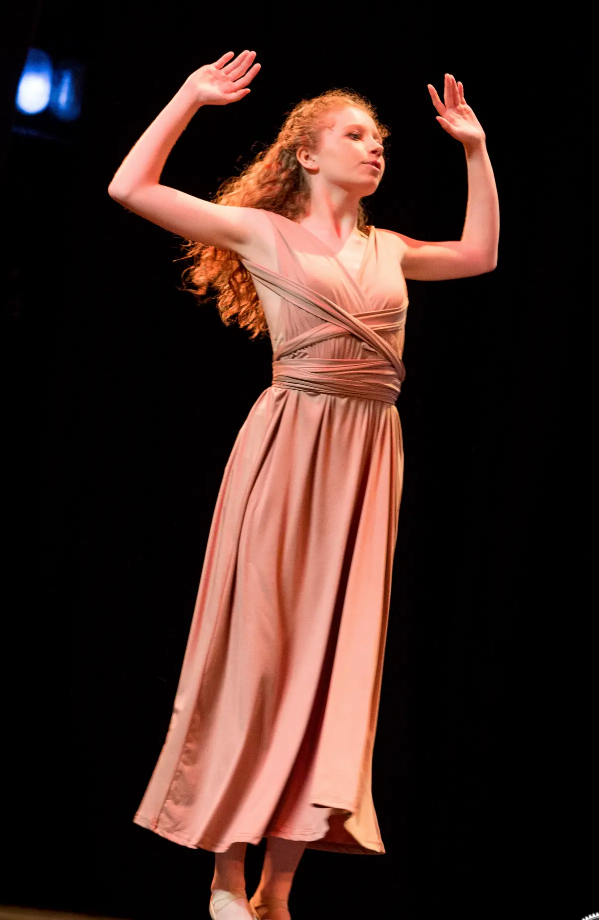 Una bailarina con vestido largo levanta los brazos.
