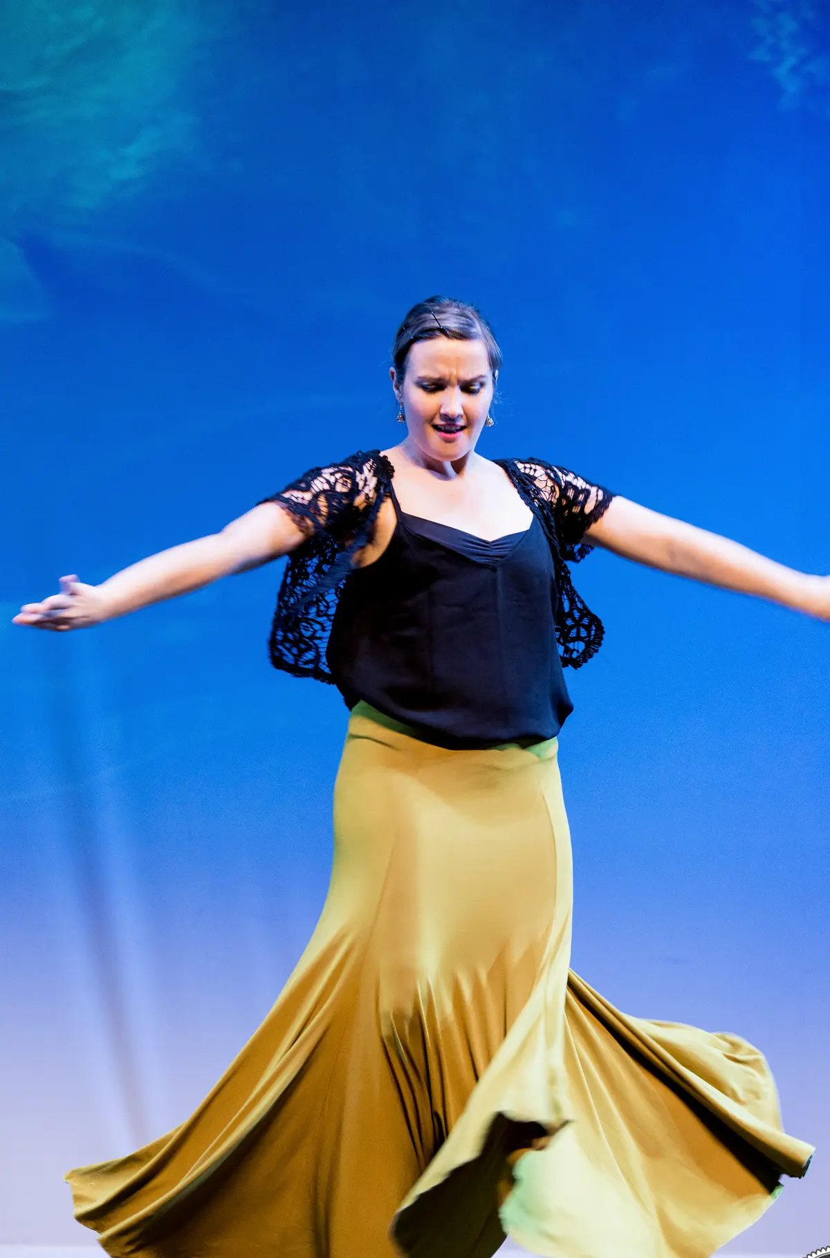 Una bailarina gira con una falda amplia de color mostaza.