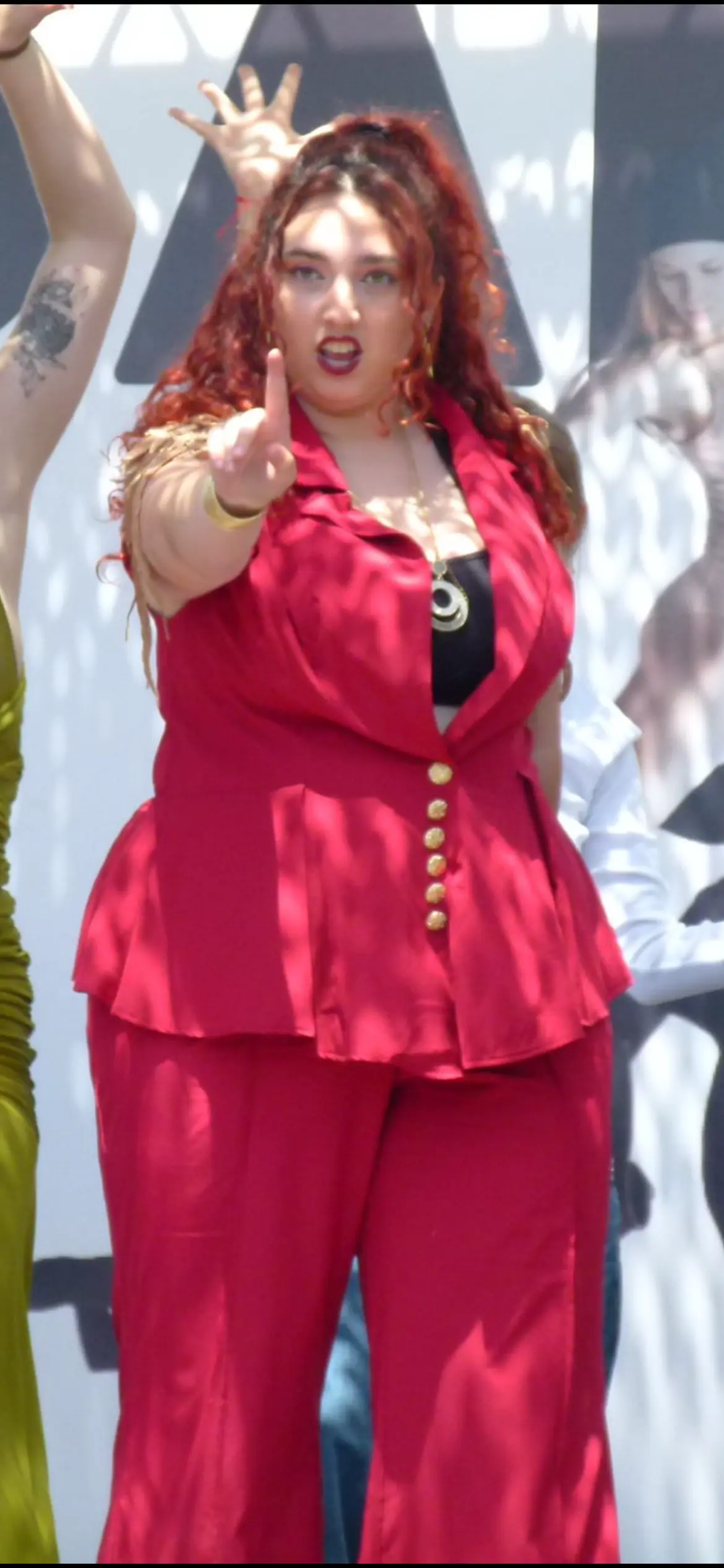 Una intérprete con traje rojo señala a cámara.