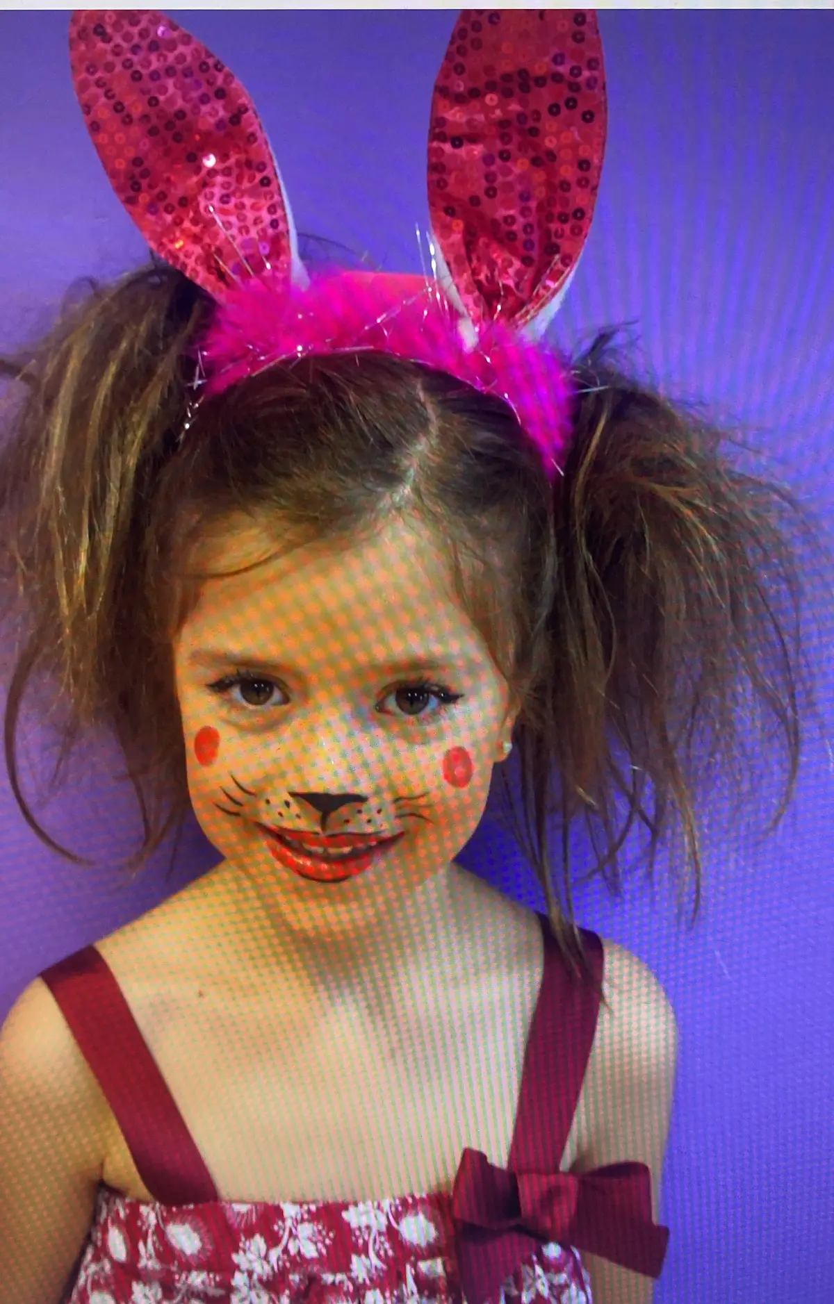 Foto de archivo: una niña con orejas de conejo y la cara pintada.