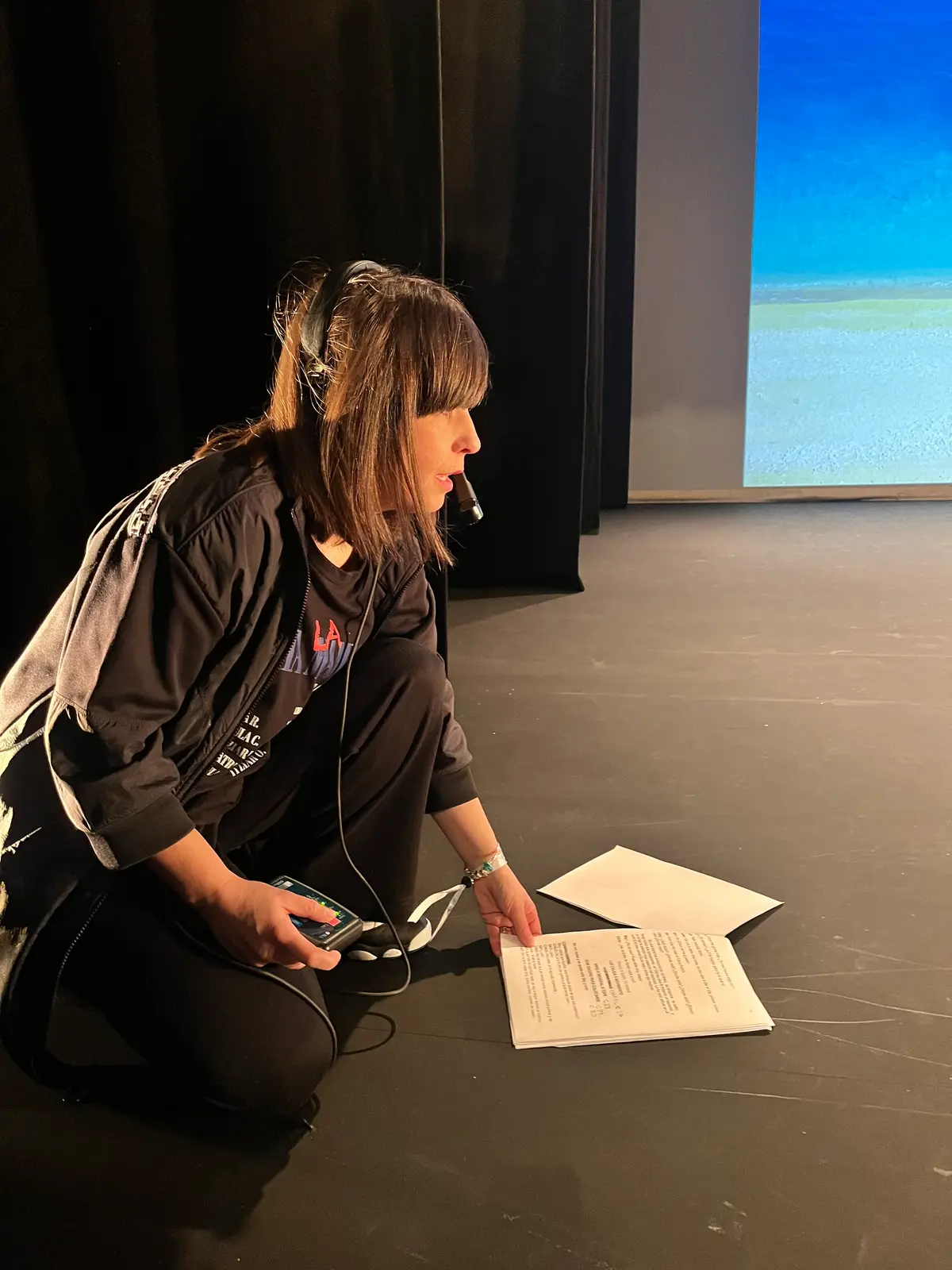 Una directora con auriculares de regiduría repasa el guion sentada en el escenario.